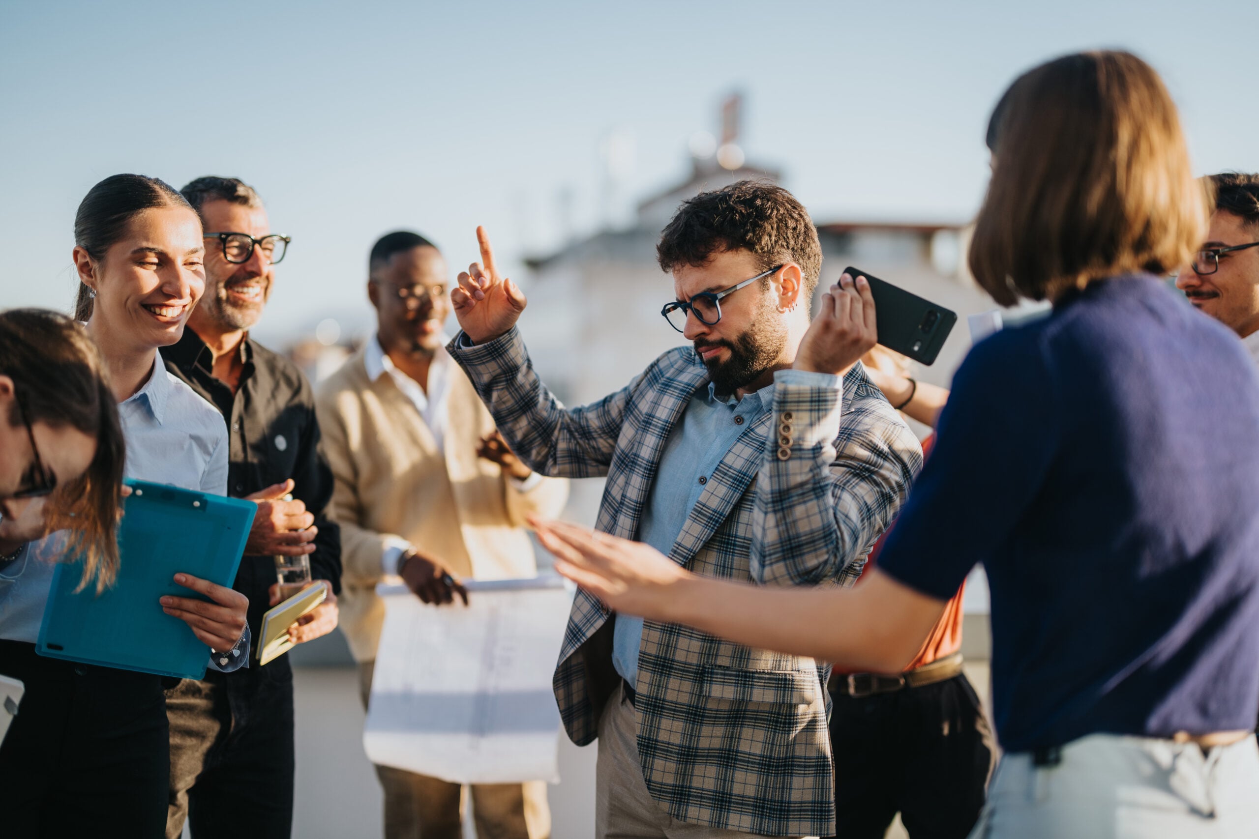 Diverse business team celebrating together on rooftop at sunset
